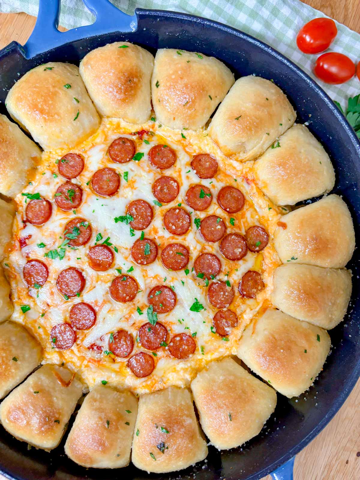 a pizza dip ring with pizza dough balls and a pizza dip in the middle is in a cast iron skillet.