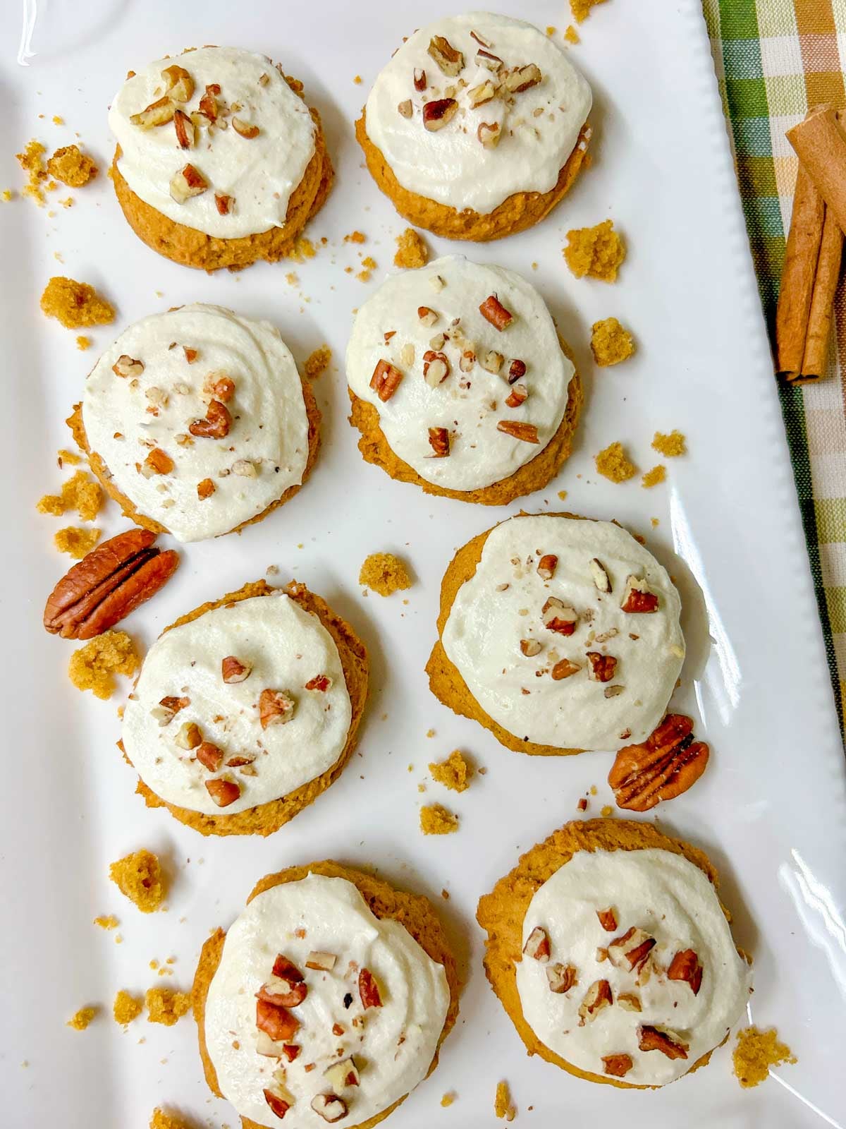 a white platter is filled with pumpkin spice cookies with cream cheese frosting
