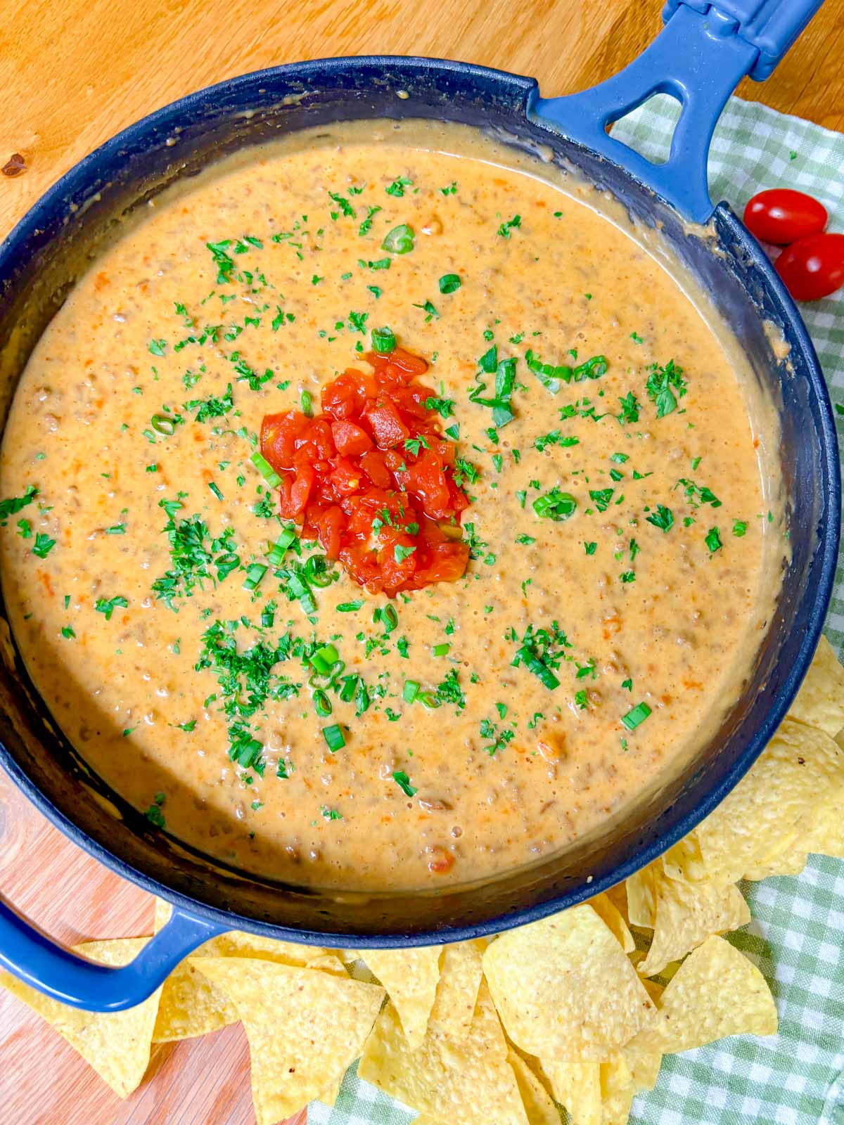 a cast iron skillet is filled with rotel dip and garnished with tomatoes and cilantro.
