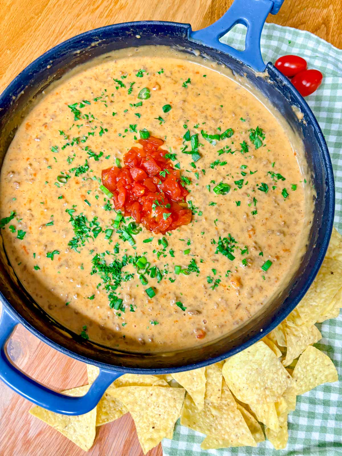 a cast iron skillet is filled with rotel dip and garnished with tomatoes and cilantro.