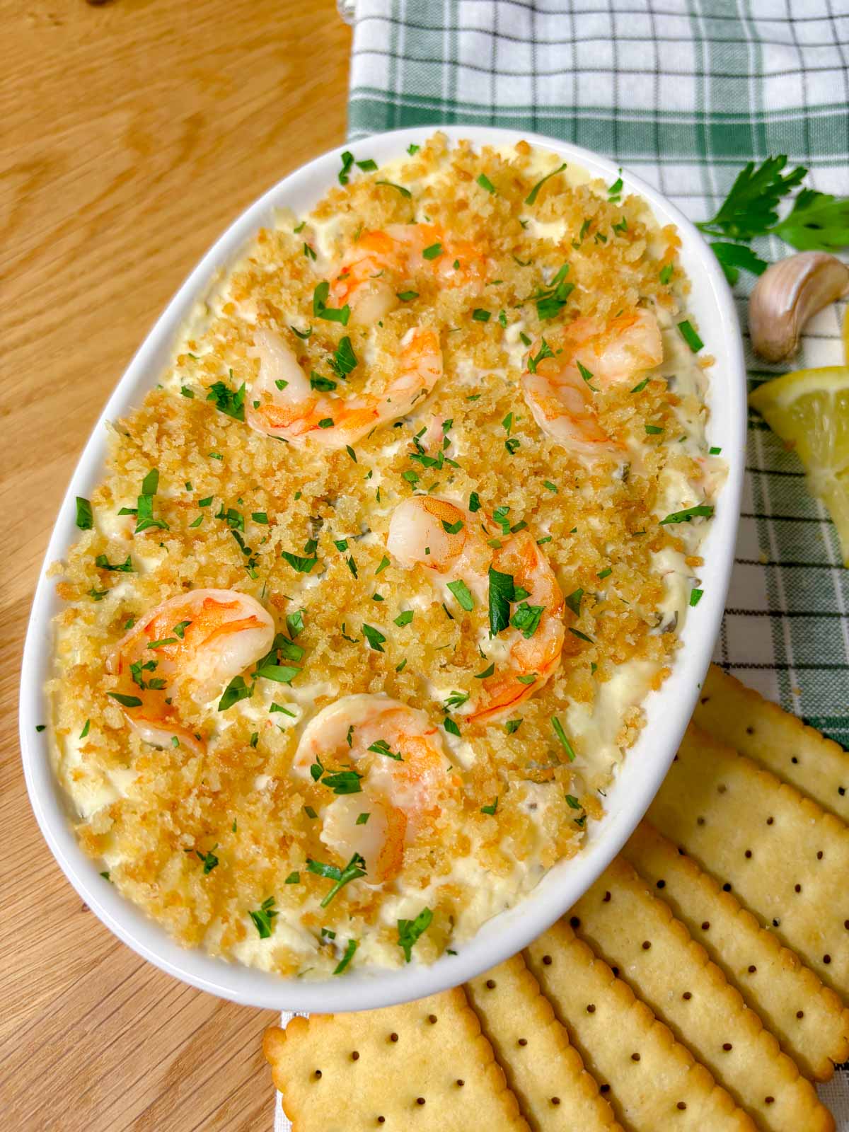 a white baking dish is filled with shrimp scampi dip and garnished with breadcrumbs and parsley