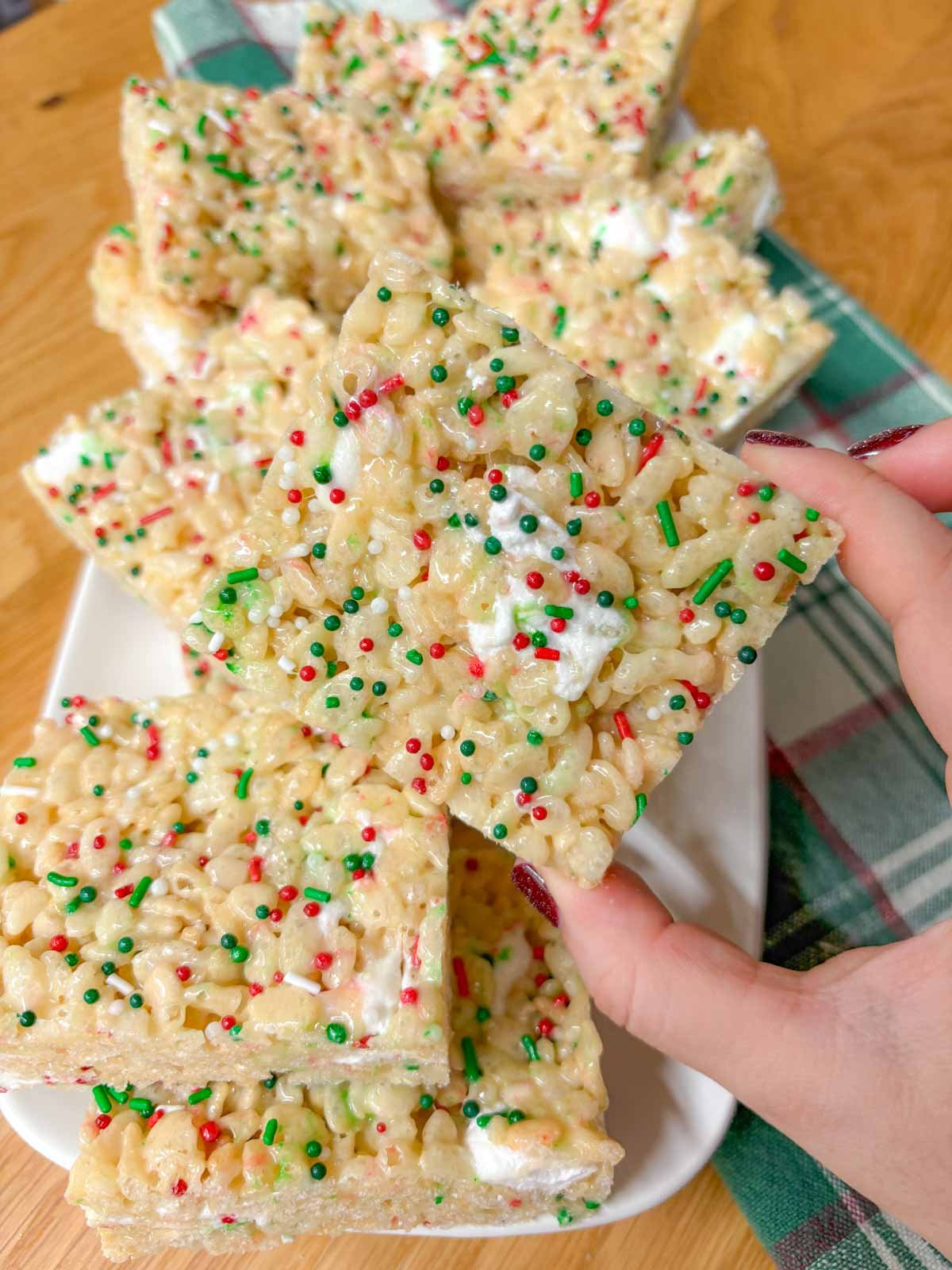 a white platter of sugar cookie rice krispie treats.  one is held close to camera