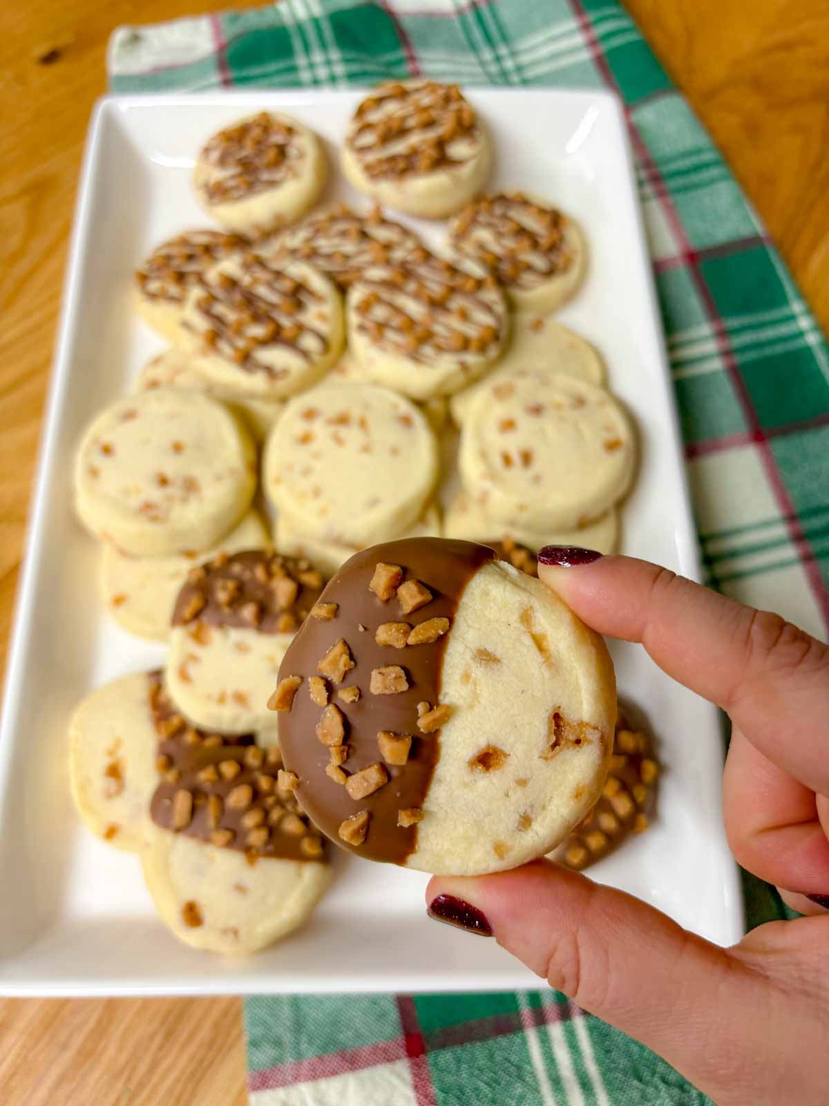 a half dipped in chocolate whipped toffee cookie is held close to camera
