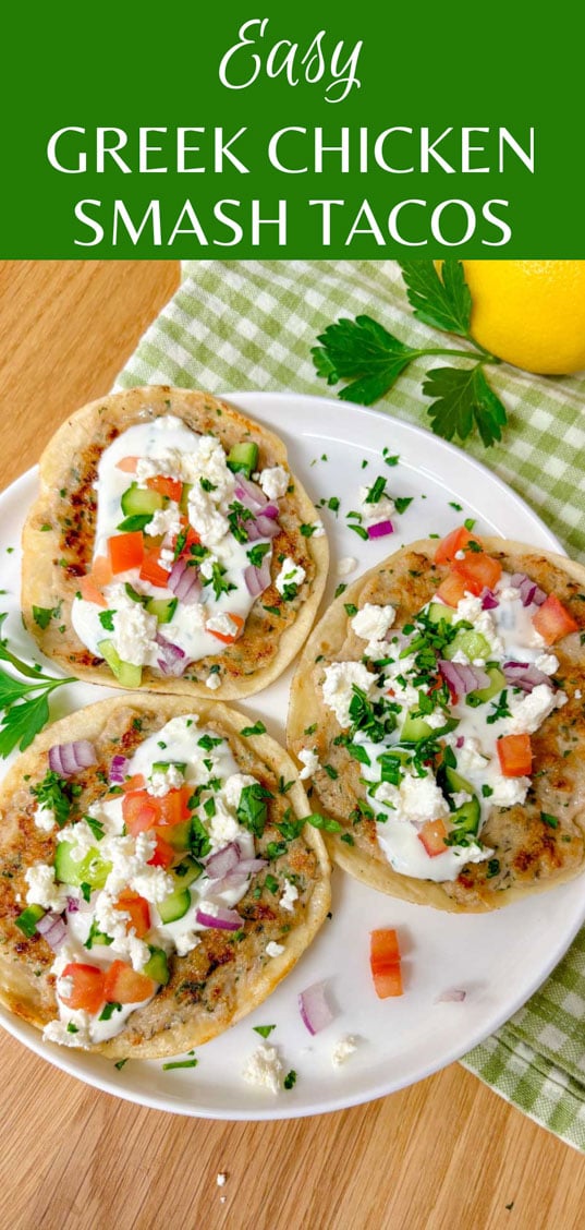 a plate is filled with three greek chicken smash tacos topped with tzatziki, onion, tomato, cucumber, onion, feta, and parsley.