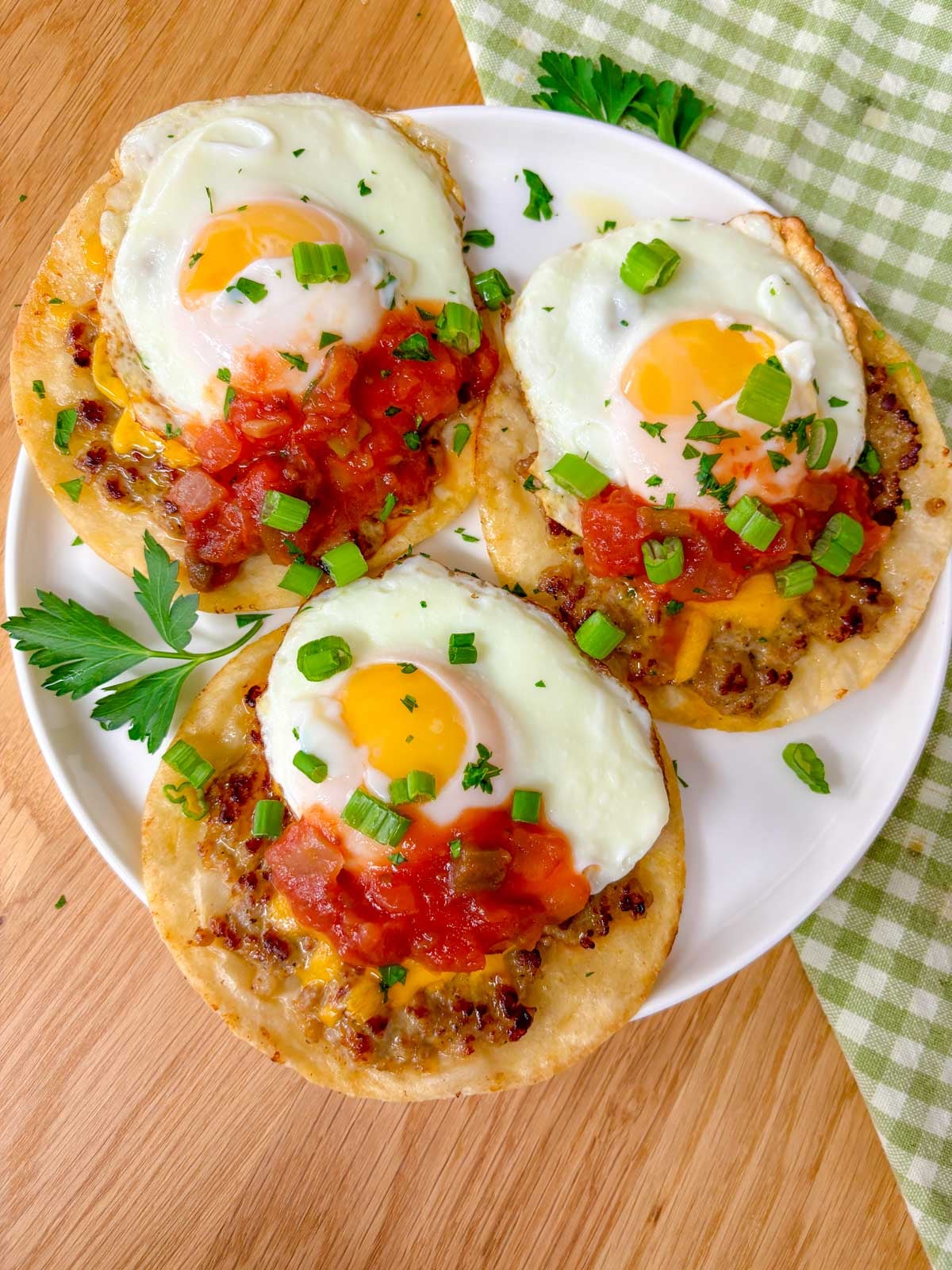 three breakfast tacos with over easy eggs on top on a plate