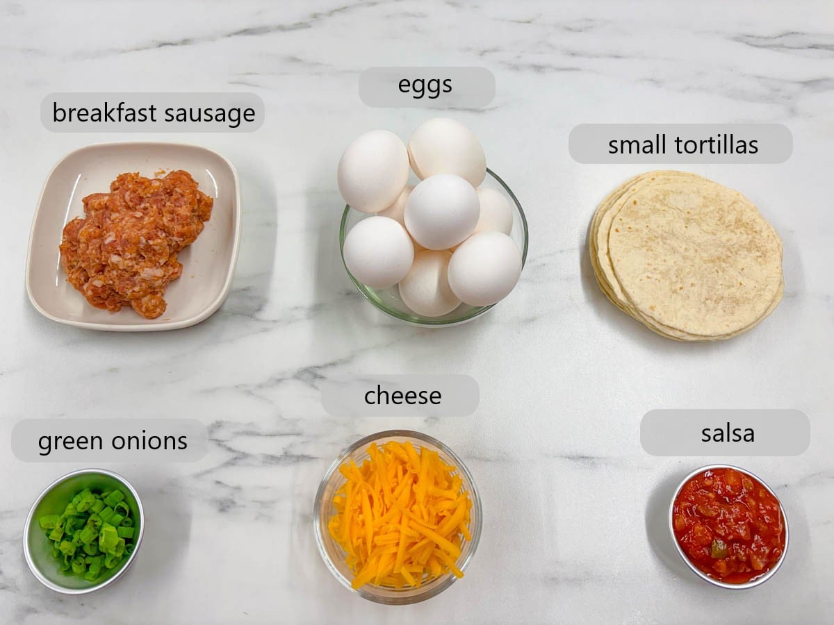 kitchen counter with ingredients and text overlays reading breakfast sausage, eggs, small tortillas, green onions, cheese, and salsa.