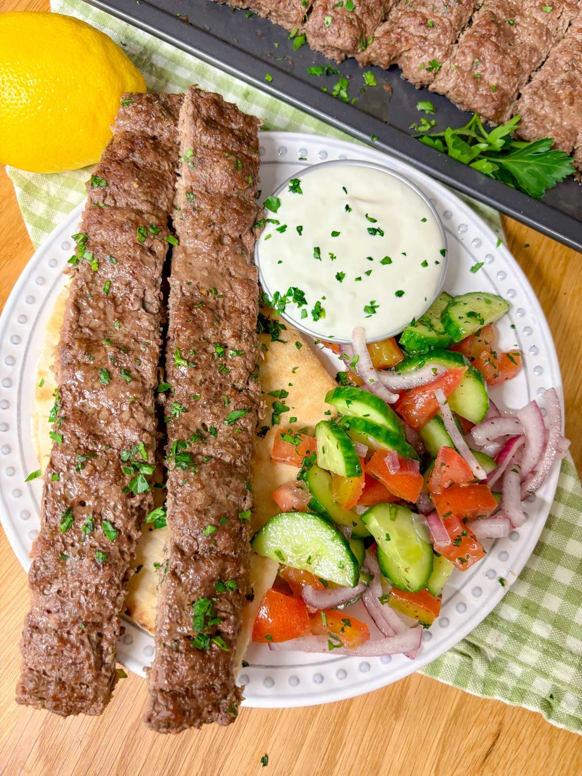 dinner plate with the kebab, garlic sauce, salad and pita bread