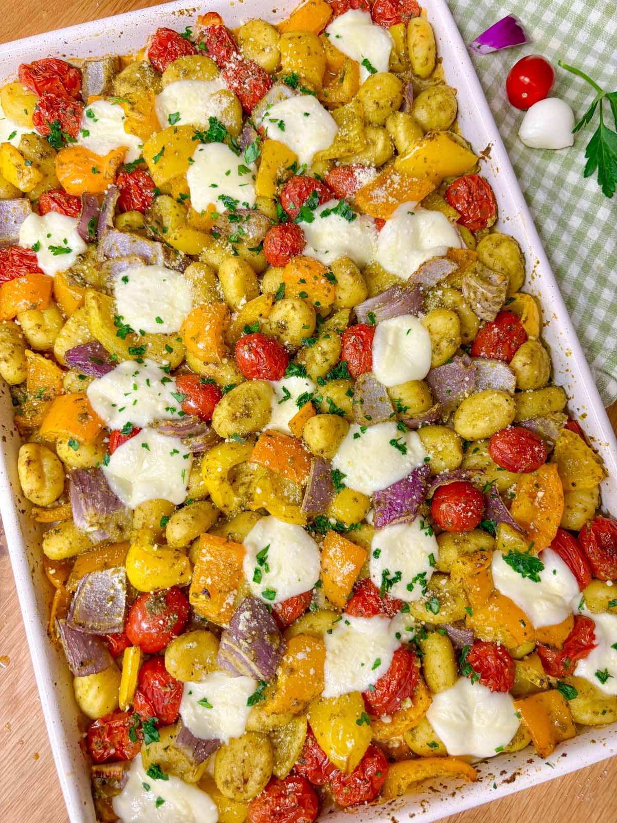 a sheet pan is filled with cheesy pesto gnocchi and garnished with parmesan, basil and parsley