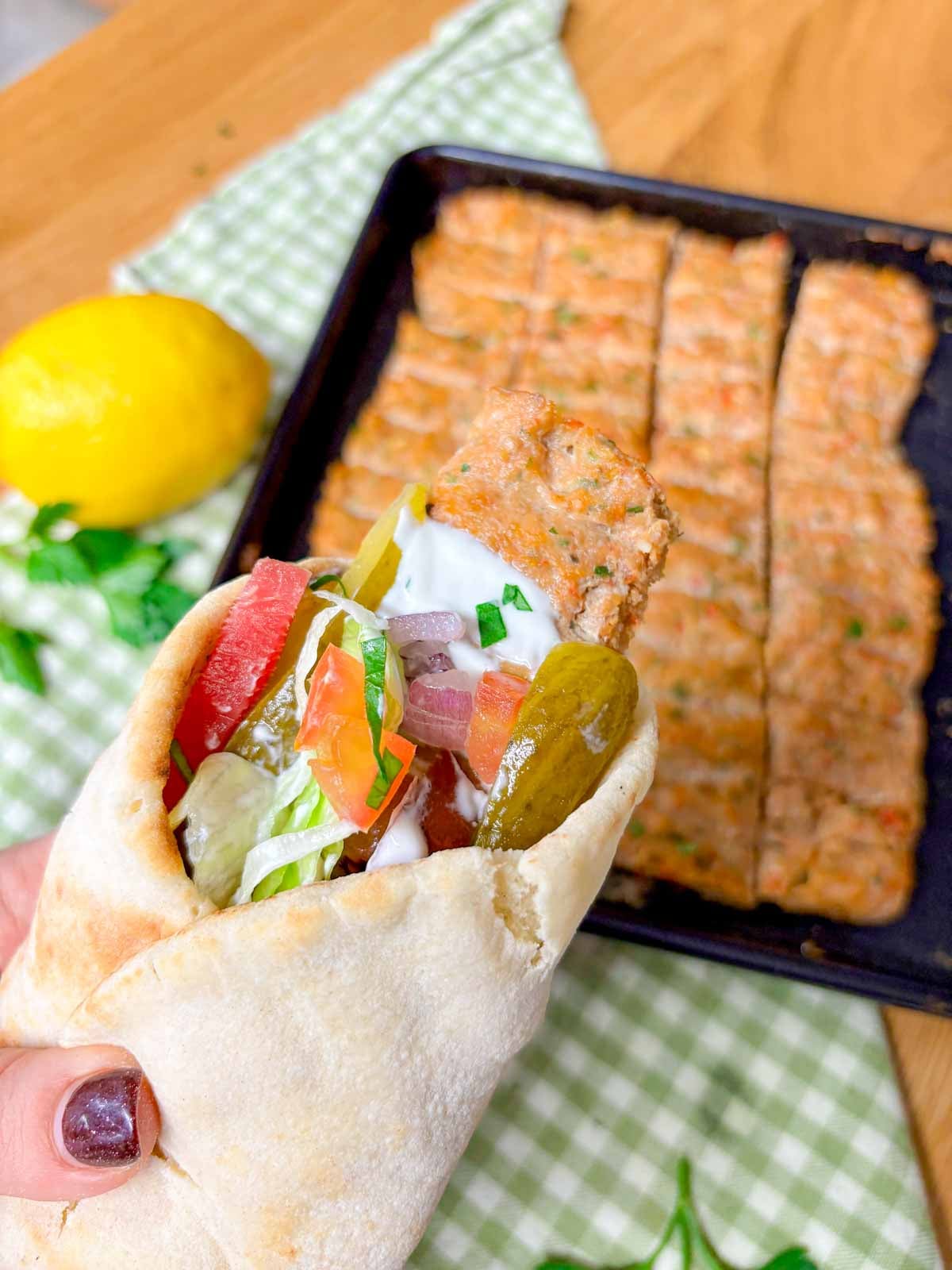 a chicken kebab wrap is held in front of camera