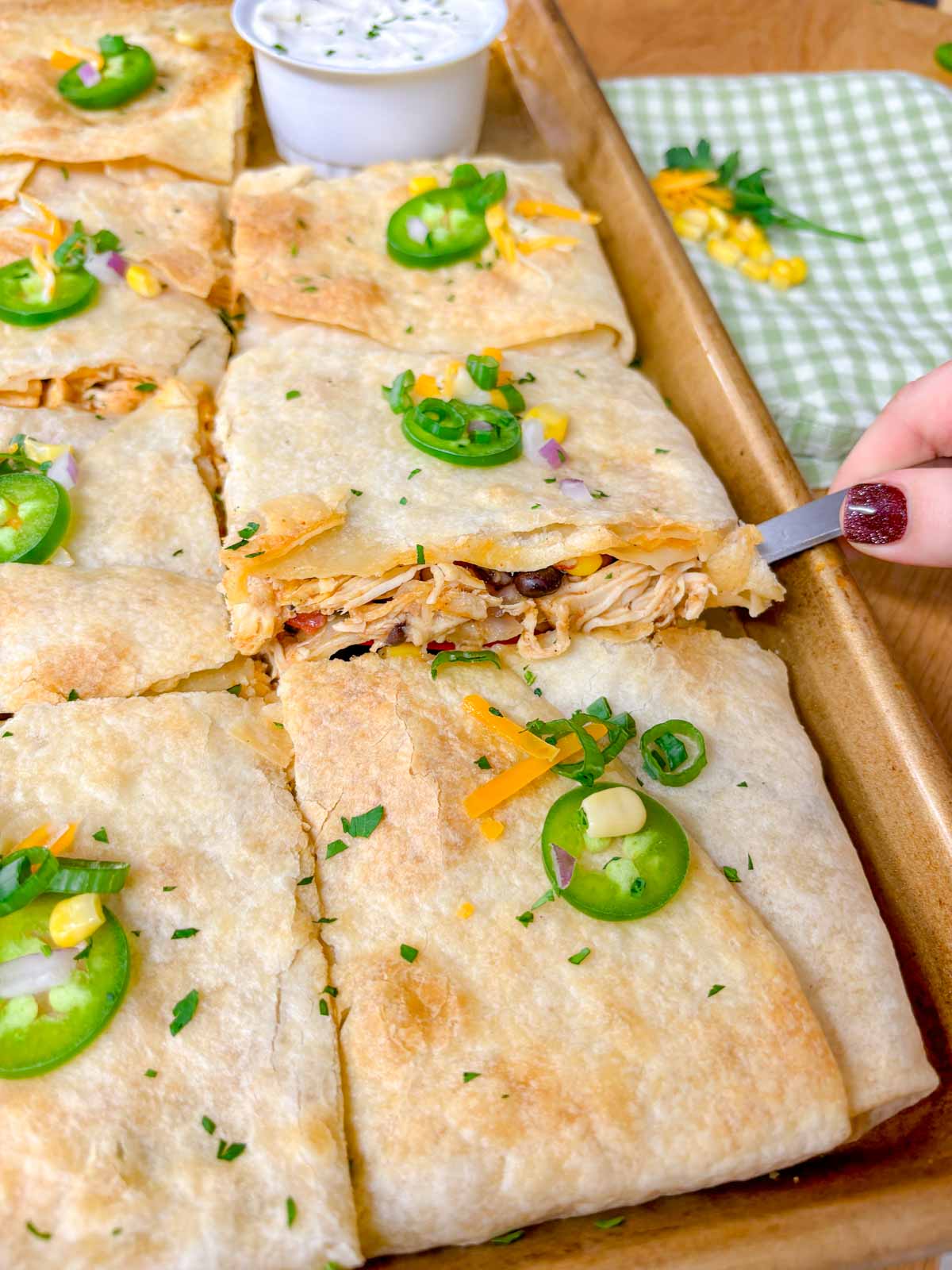 a sheet pan is filled with a loaded chicken quesadilla and cut into 12 pieces.