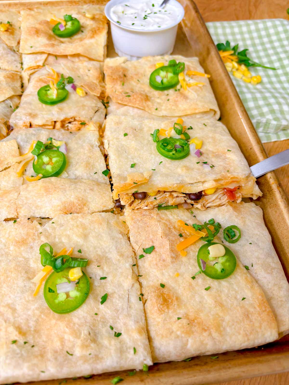 a sheet pan is filled with a loaded chicken quesadilla and cut into 12 pieces.