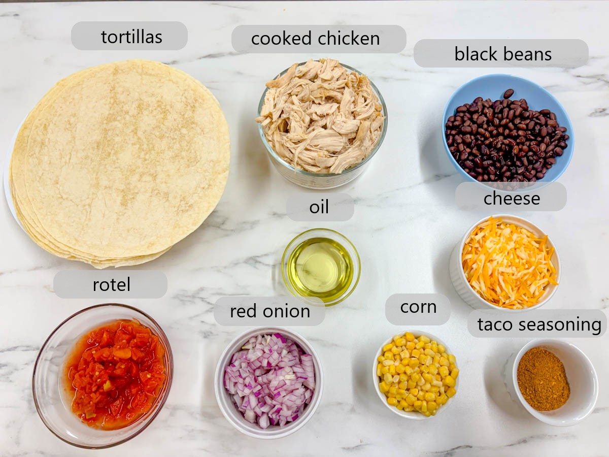 kitchen counter with bowl of ingredients with text overlays reading tortillas, cooked chicken, black beans, oil, cheese, rotel, red onion, corn, taco seasoning