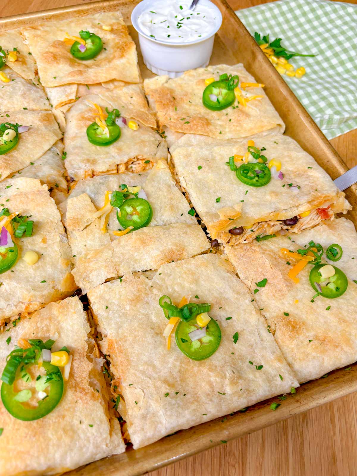 a sheet pan is filled with a loaded chicken quesadilla and cut into 12 pieces.