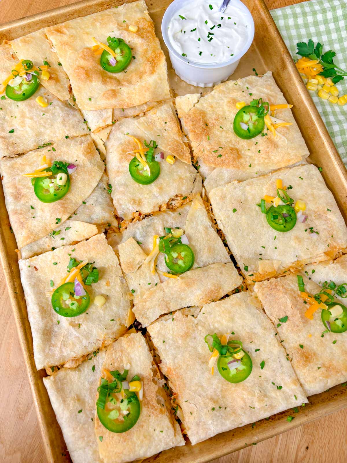 a sheet pan is filled with a loaded chicken quesadilla and cut into 12 pieces.