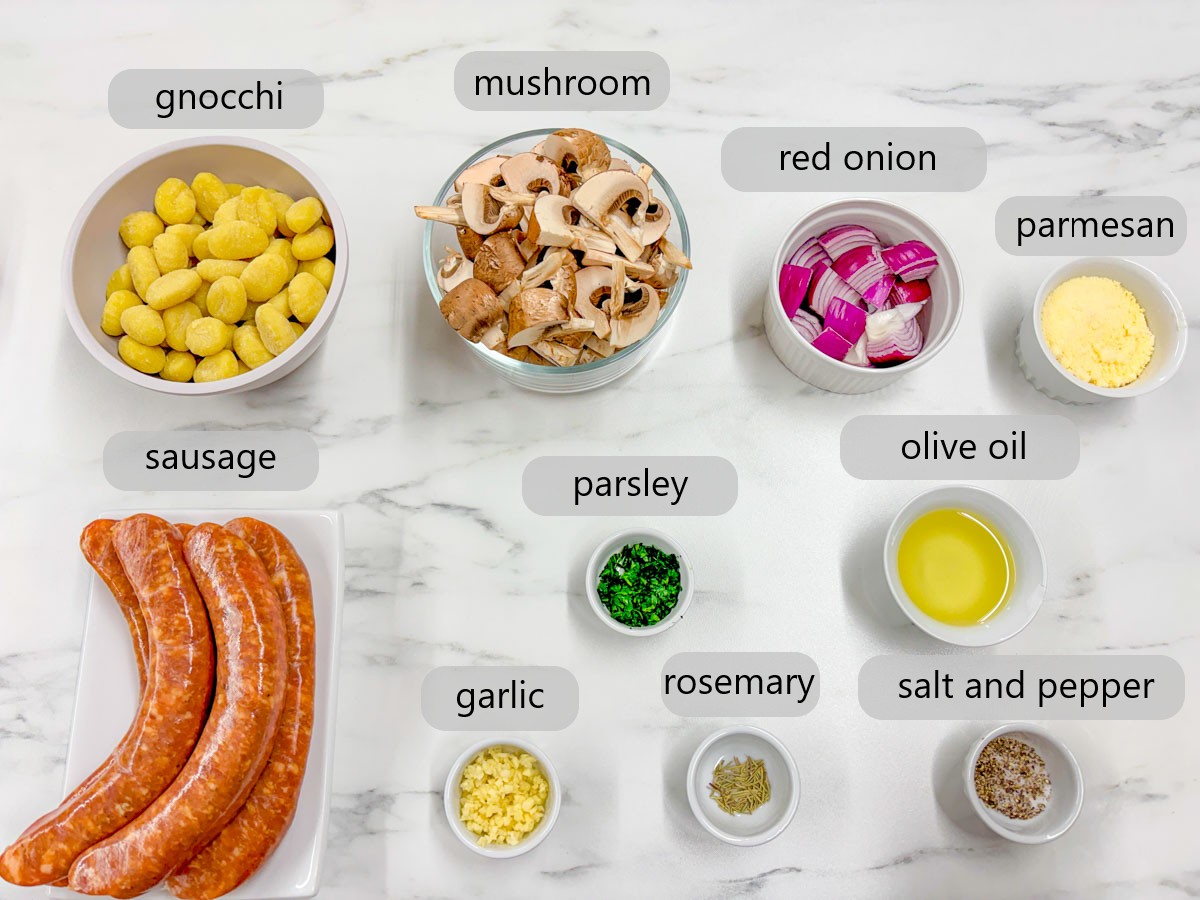 kitchen counter with bowls of ingredients and text overlays reading gnocchi, mushroom, red onion, parmesan, sausage, parsley, olive oil, garlic, rosemary, salt and pepper.