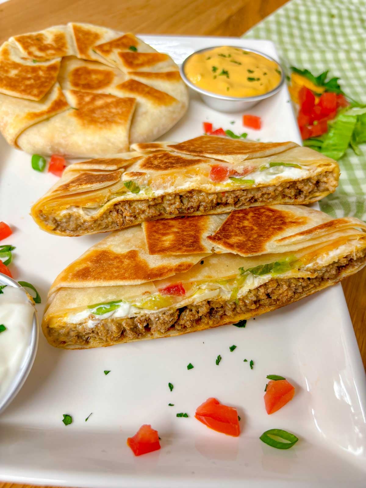 a white plate has two crunchwrap supremes on it. one is cut in half and stacked