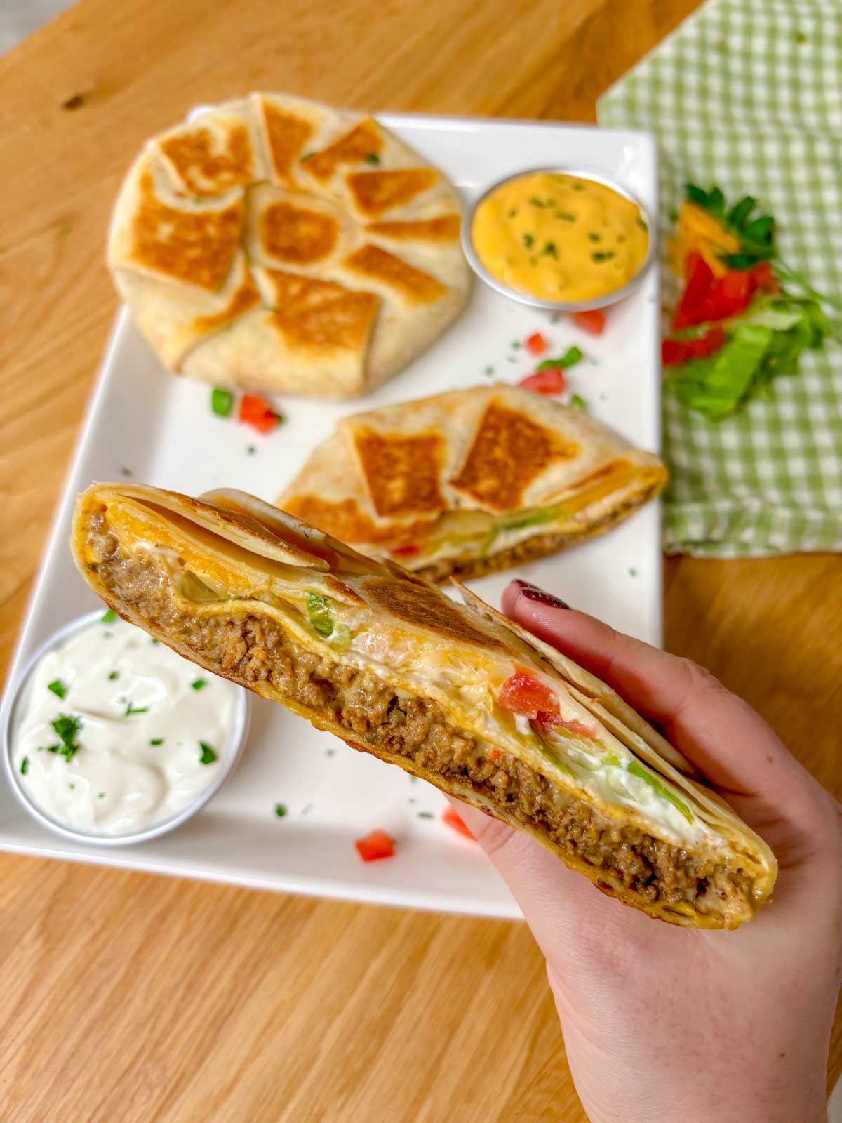 a white plate has two crunchwrap supremes on it. one is cut in half and stacked