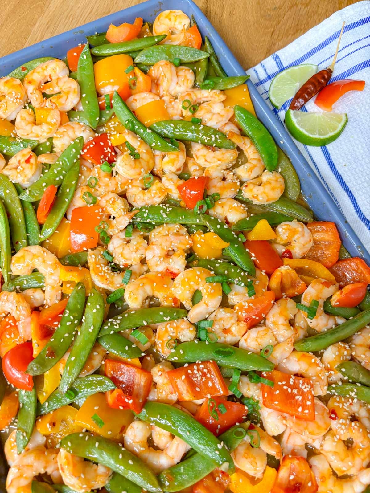a sheet pan filled with shrimp and veggies tossed in a sweet chili sauce