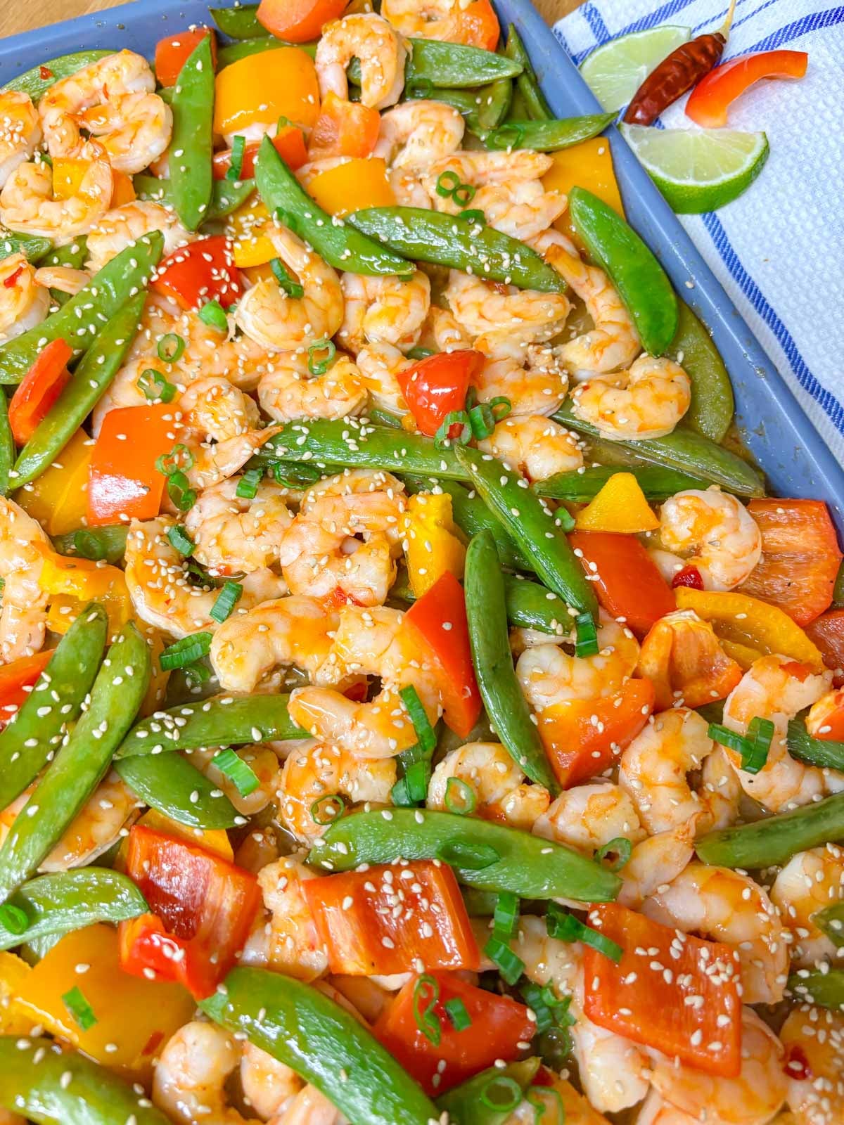 close up shot of a sheet pan with roasted shrimp and veggies cooked in a sweet chili sauce