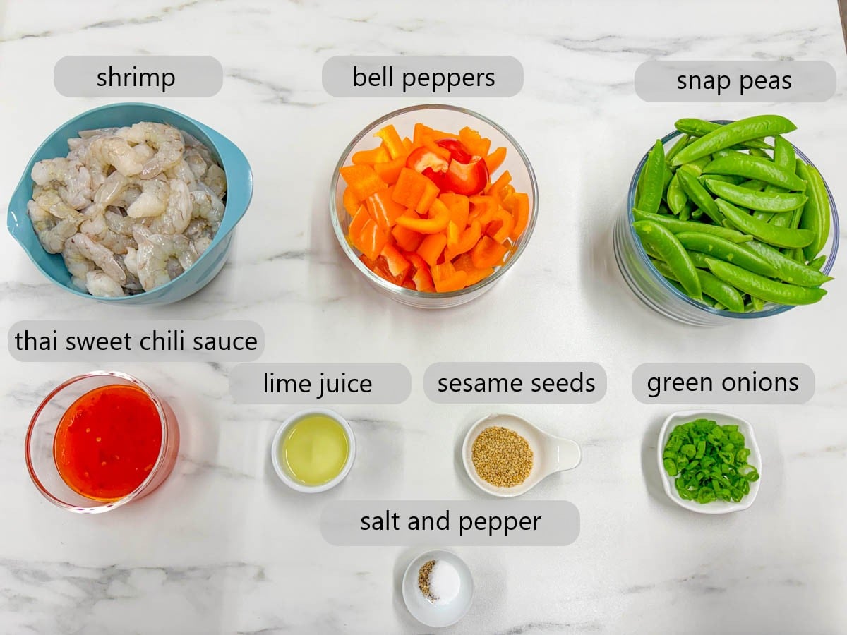 kitchen counter with bowls of ingredients and text overlays reading shrimp, bell peppers, snap peas, Thai sweet chili sauce, lime juice, sesame seeds, green onions, salt, and pepper.