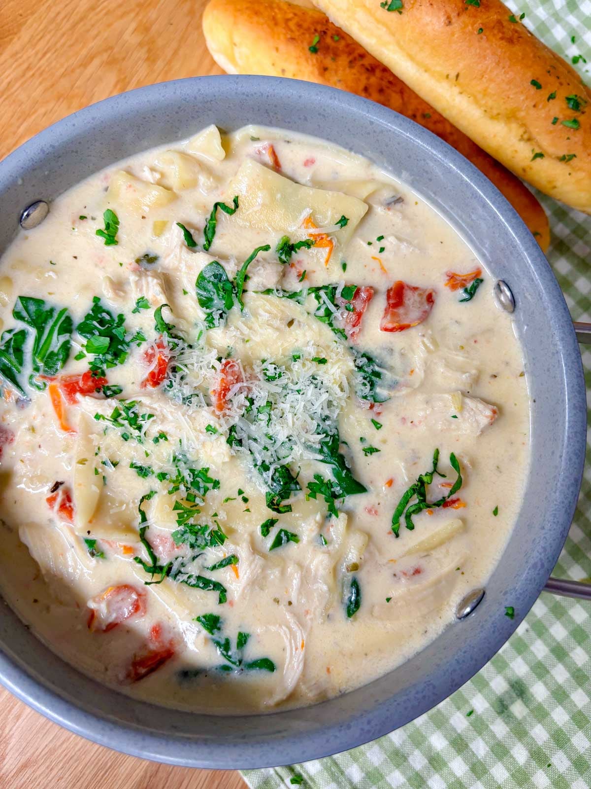 a pot of white chicken lasagna soup with breadsticks on the side