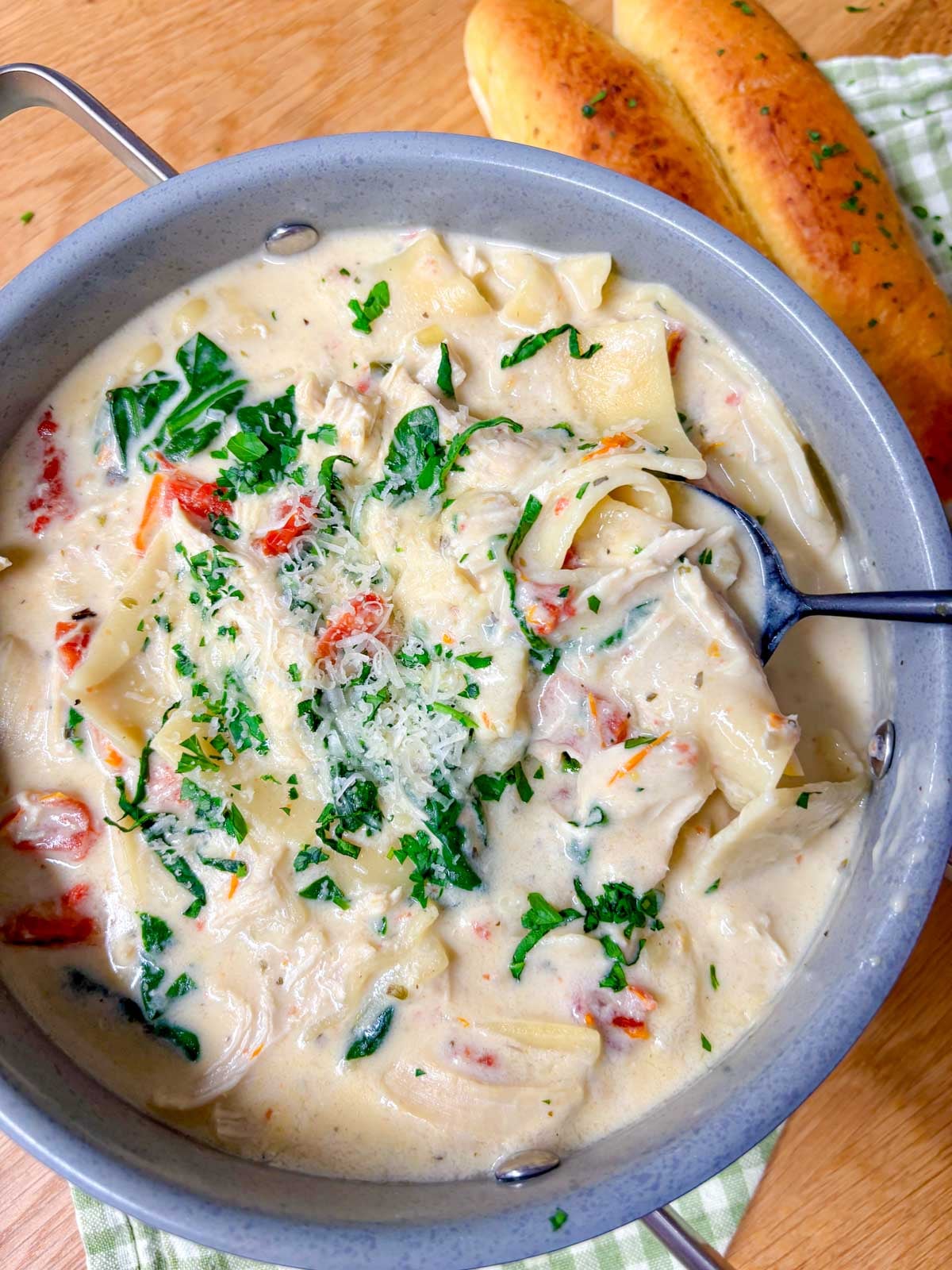 a pot of white chicken lasagna soup and breadsticks on the side