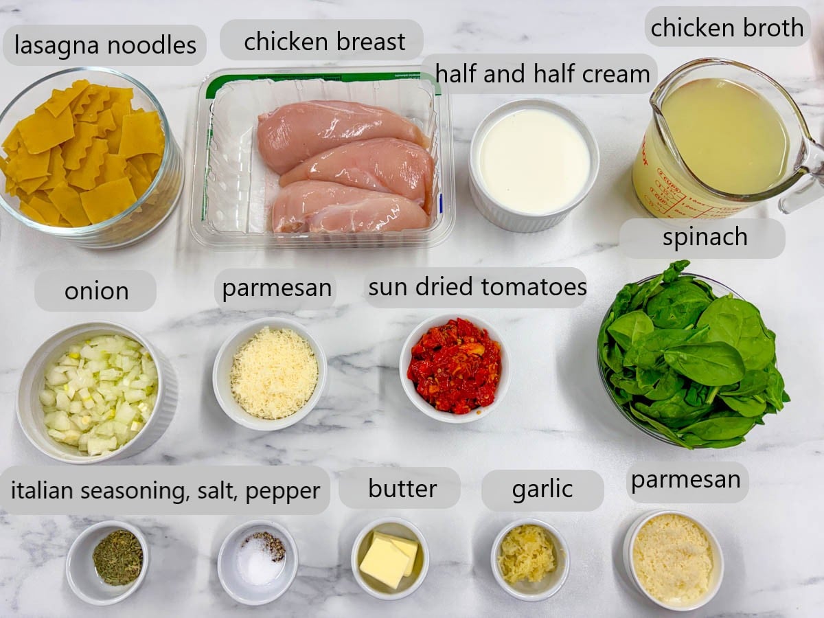 kitchen counter with ingredients and text overlays reading lasagna noodles, chicken breast, half and half cream, chicken broth, onion, parmesan, sundried tomatoes, spinach, Italian seasoning, salt, pepper, butter, garlic, parmesan