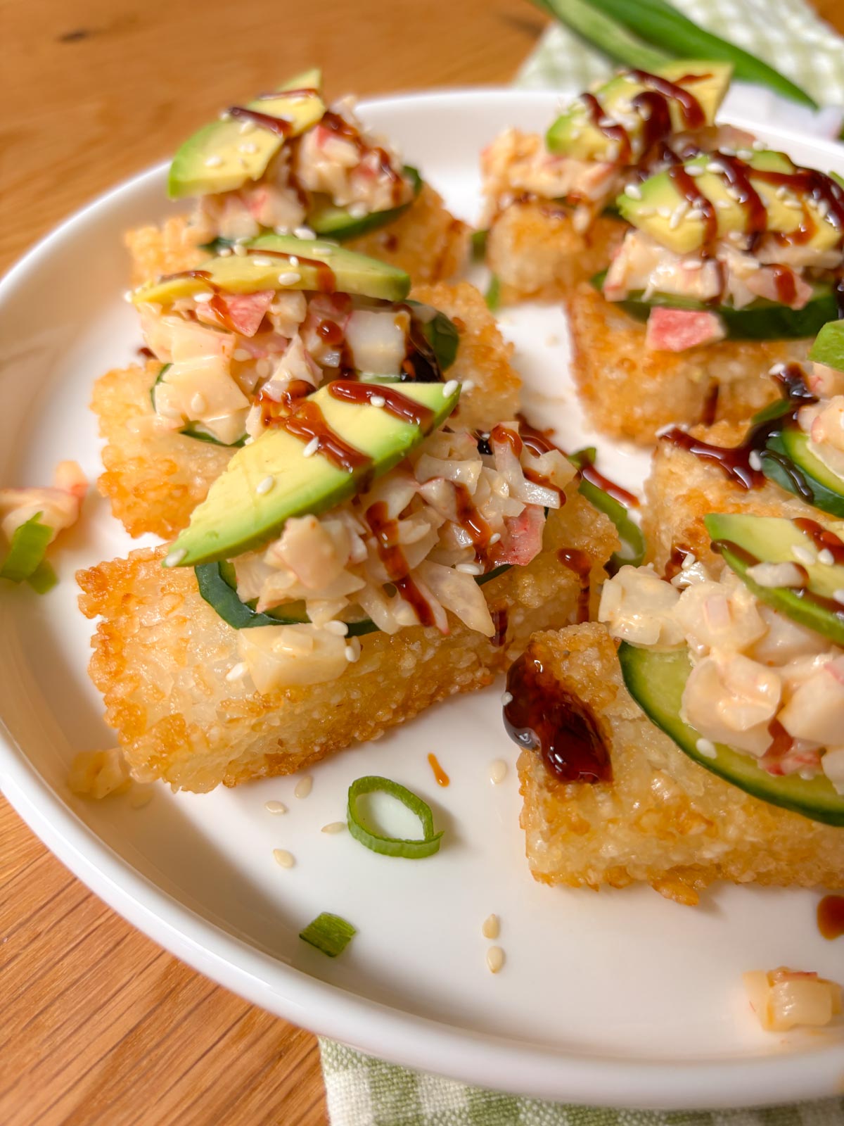 close up shot of a piece of spicy California roll crispy rice drizzled with eel sauce