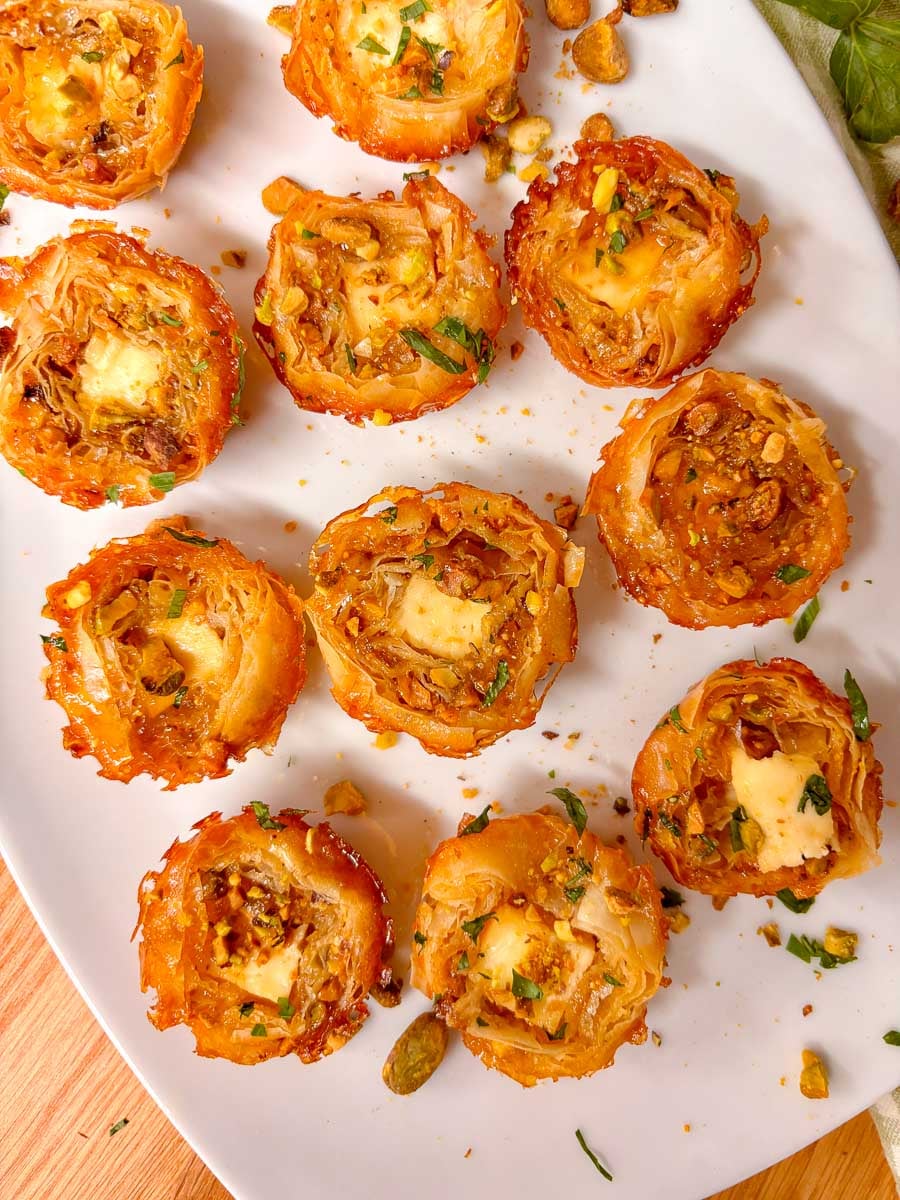 a white plate is filled with honey feta pistachio bites