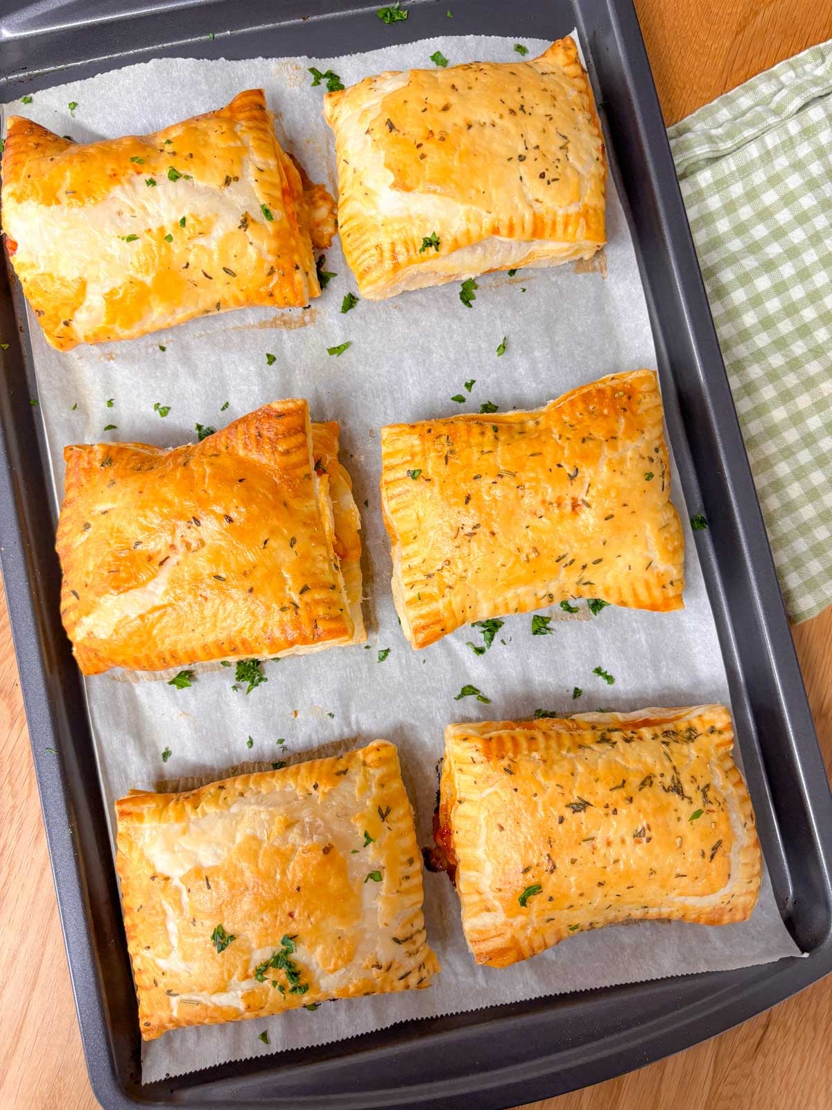 a baking tray with 6 baked hot honey pizza pockets garnished with parsley